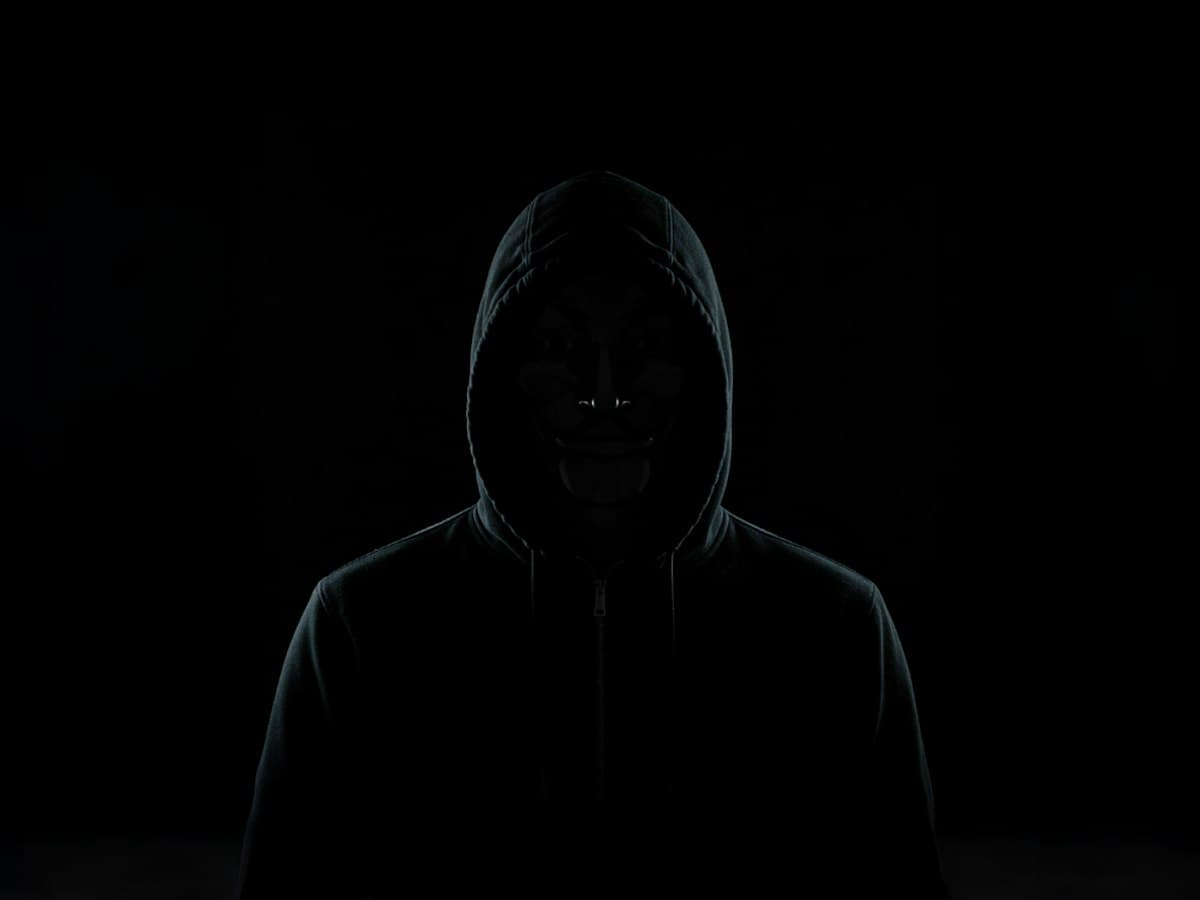 Silhouette of a hooded figure at a laptop, representing an active cyber threat